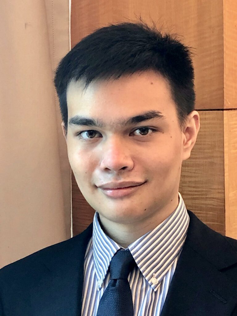 Headshot of FairVote staff member Bryan Huang in front of a brown wooden background