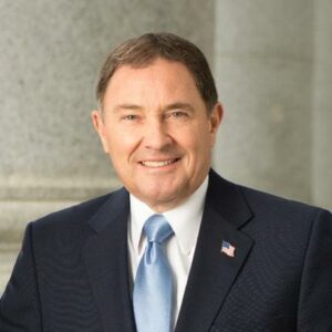 Photo of former governor Gary Herbert wearing an American flag pin and standing in front of stone columns,