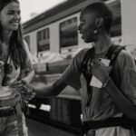 Photo of two friends talking on a train platform