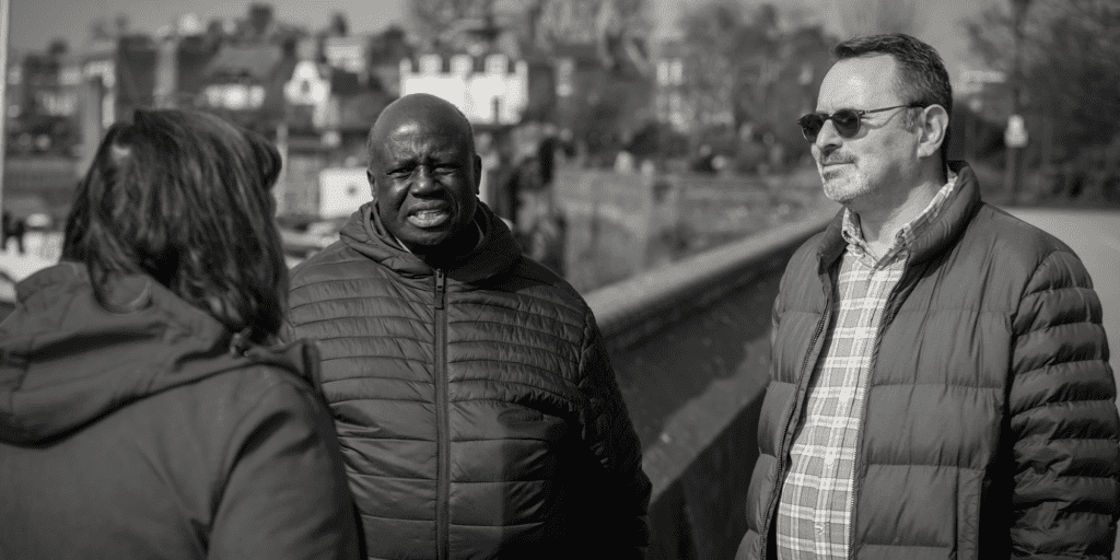 Photo of three people talking on a bridge