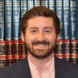 Photo of Ben Williams standing in front of a shelf of law books