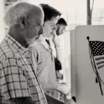 Photo of several voters standing at a voting booths filling out their ballots