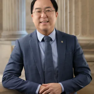 Andy Kim wearing a suit and standing in front of the columns of the U.S. Capitol